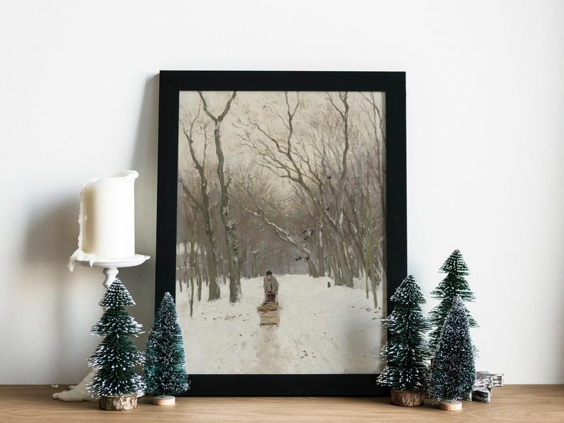 Framed winter landscape painting features a lone figure on a snowy path lined with bare trees. Candle and miniature evergreen trees add a festive touch.