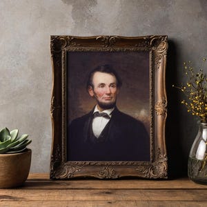 A framed portrait of a man in a suit is on a wooden table. Beside it, a potted succulent and a clear vase with branches add a natural touch.