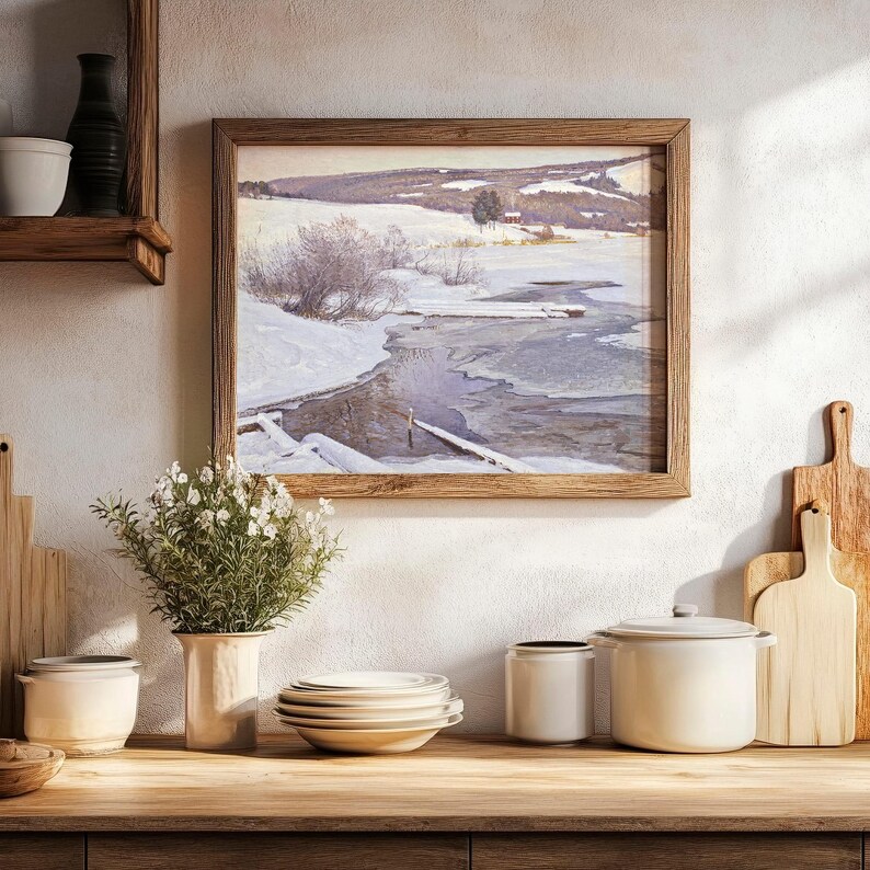 A cozy kitchen scene features a wooden shelf, stacked plates, and jars. A framed winter landscape painting hangs above a vase with flowers. Warm tones prevail.