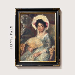 A framed portrait of a woman in a vintage dress, holding a fan, with a calm expression. She wears a delicate bonnet, and the frame is ornate.