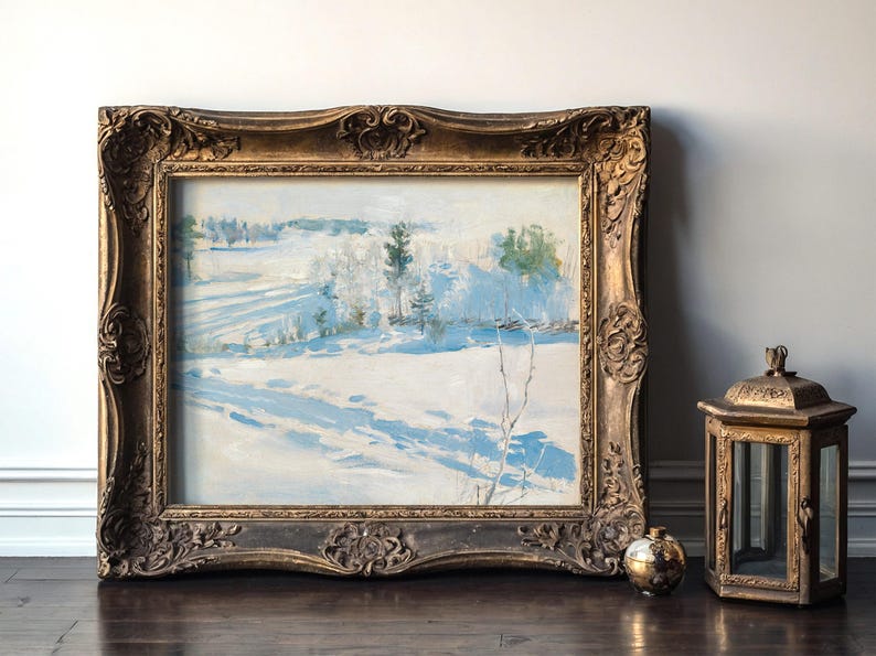 An ornate framed painting of a snowy landscape rests against a wall. A vintage lantern and small metallic sphere sit beside it on the wooden floor.