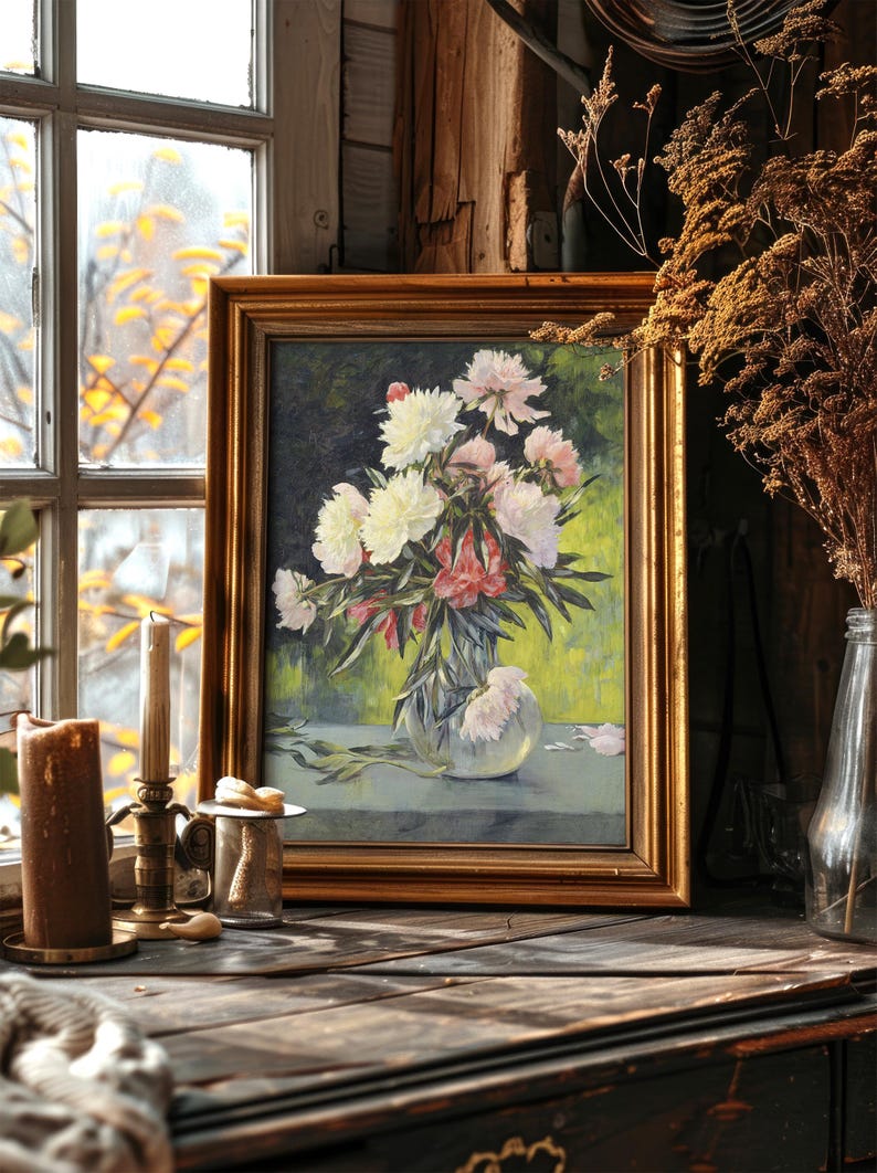 Framed painting of a floral bouquet in a vase on a wooden table by a window. Warm sunlight casts a cozy glow over candles and dried plants nearby.