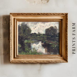 Ornate gold-framed painting of a serene river landscape with reflections, overcast sky, and lush greenery. Text reads "PRINTS FARM" on a textured wall.