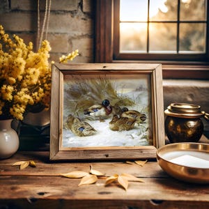 Framed painting of ducks in a snowy landscape on a wooden table with yellow flowers, a lit candle, and leaves. Sunlight streams through a window.