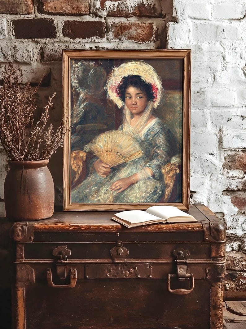 Framed vintage portrait of a woman with a fan, resting on an old chest against a brick wall. A vase of dry twigs and an open book add rustic charm.