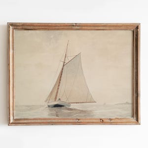 A framed watercolor painting of a sailboat with white sails on a calm sea. The painting is in a light brown wooden frame.