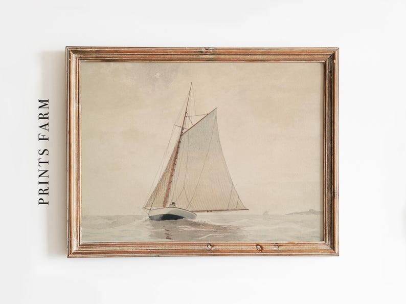 A framed watercolor painting of a sailboat with white sails on a calm sea. The painting is in a light brown wooden frame.