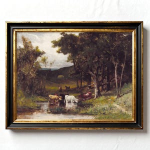Framed painting of a serene landscape with a small herd of cows drinking from a stream, surrounded by trees and lush greenery under a cloudy sky.