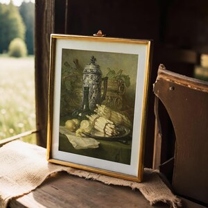 Framed still life painting on wooden surface near window. Shows ornate jug, lemons, asparagus, and wine bottle, conveying a rustic, calm ambiance.