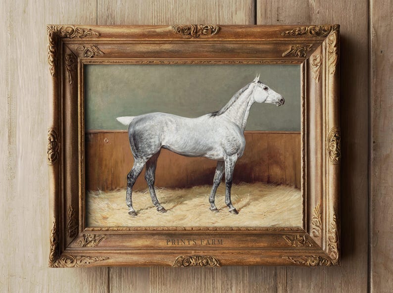 Framed painting of a white horse standing on hay, with a wooden wall background. Ornate gold frame contrasts with the rustic setting.