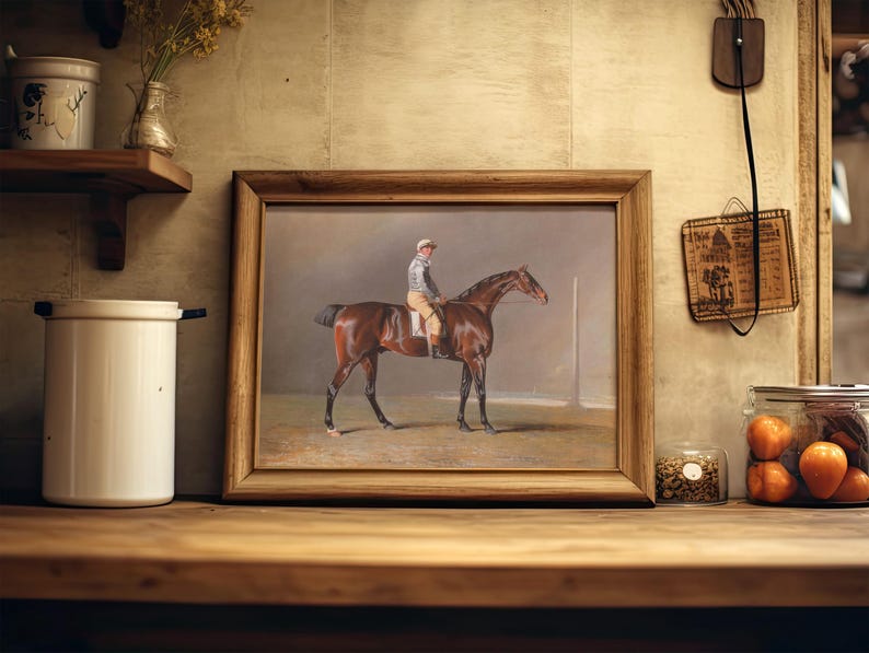 A framed painting of a jockey on a horse is resting on a wooden shelf in a rustic kitchen. Nearby, jars hold spices and vibrant orange tomatoes.