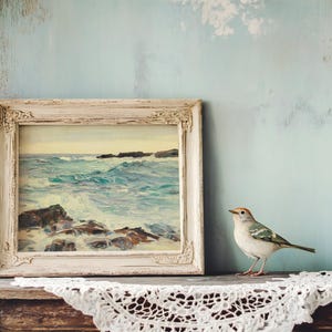 A small bird perches on a wooden shelf next to a framed ocean painting. The wall is textured blue, creating a serene, vintage atmosphere.
