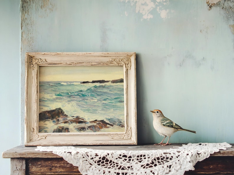 A small bird perches on a wooden shelf next to a framed ocean painting. The wall is textured blue, creating a serene, vintage atmosphere.