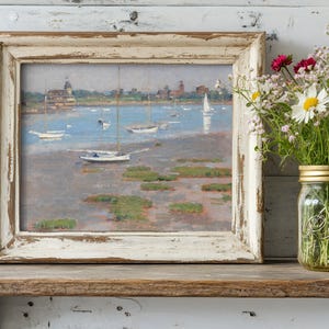 A rustic, framed painting of boats on a serene lake rests on a wooden shelf. Beside it, a mason jar holds colorful wildflowers, creating a calm, nostalgic tone.