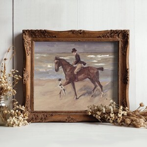 Framed painting of a horseback rider and dog on a beach, with gentle waves in the background. Surrounded by dried flowers, conveying a nostalgic and serene ambiance.