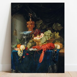The image is a detailed still life painting featuring an array of fruits, a lobster, and decorative objects arranged on a richly textured blue cloth, with a dark draped background. Prominent items include green and red grapes, a halved peach, a lemon, a tomato, and a peeled lemon peel, along with a large red lobster, a loaf of bread, and a decorative silver and blue dish. There is also an ornate, golden finial at the top, adding a touch of elegance to the scene.