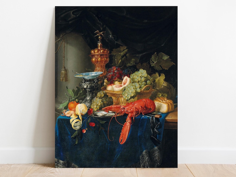 The image is a detailed still life painting featuring an array of fruits, a lobster, and decorative objects arranged on a richly textured blue cloth, with a dark draped background. Prominent items include green and red grapes, a halved peach, a lemon, a tomato, and a peeled lemon peel, along with a large red lobster, a loaf of bread, and a decorative silver and blue dish. There is also an ornate, golden finial at the top, adding a touch of elegance to the scene.