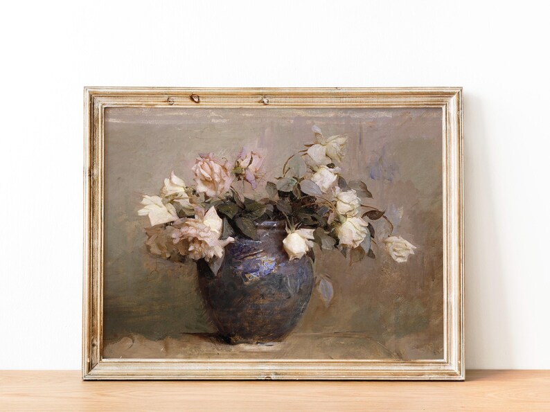 A framed painting of a still life featuring a blue ceramic vase filled with white and pink roses. The roses are wilting and have a vintage aesthetic. The background is a muted brown.