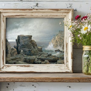 Vintage-style framed painting of a rocky coastline on a wooden shelf, next to a mason jar filled with colorful wildflowers, creating a calm, rustic scene.