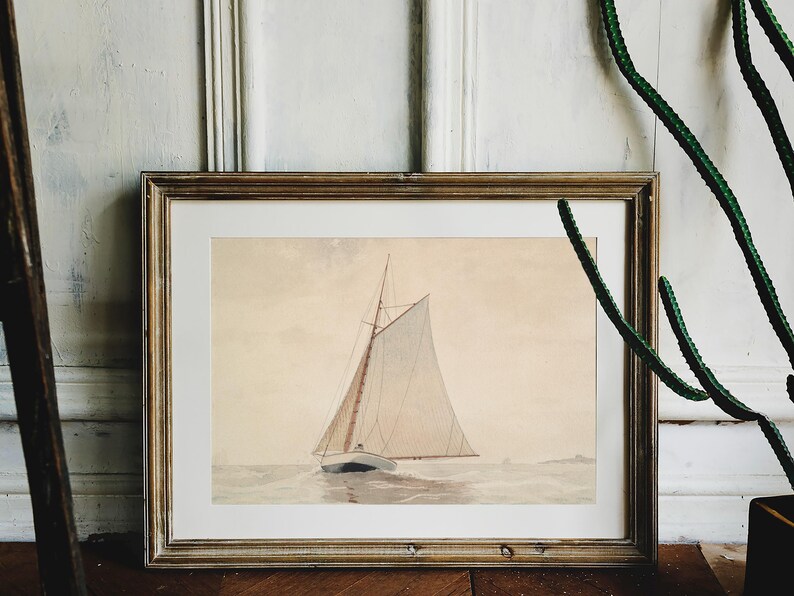 A framed watercolor painting of a sailboat with white sails on a calm body of water. The painting is in a light wood frame.