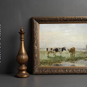 A framed painting of two cows grazing in a serene, green pasture with a distant sailboat on the horizon. An ornate vase stands beside it. Text reads, "PRINTS FARM."