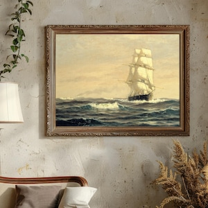 A framed painting of a tall sailing ship navigating rough seas, hung on a textured beige wall. To the left, a white lampshade on a tall lamp and a green vine with small leaves trails from the top left corner. Below the painting, part of a bed with a wooden headboard and pillows in neutral colors is visible. To the bottom right, a bunch of dried, golden-brown pampas grass is arranged in a vase.