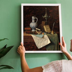 A framed painting of a still life with a blue and white ceramic pitcher, a silver oil lamp, a quill pen, and a sheet of music on a wooden table.