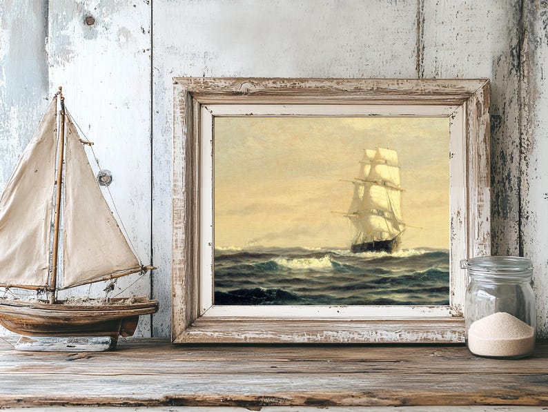 A nautical-themed still life features a model sailboat with beige sails on a wooden surface, a framed painting of a sailing ship on choppy seas in the background, and a glass jar filled with white sand beside the frame. The background consists of distressed, weathered wooden panels in shades of white and gray, enhancing the rustic and vintage ambiance.