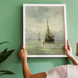 A framed painting of a seascape with three sailboats on a calm body of water. The sky is a light blue with white clouds. The water is a light blue with whitecaps. The sailboats are white with brown sails.