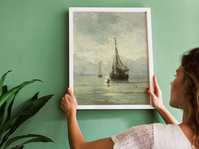 A framed painting of a seascape with three sailboats on a calm body of water. The sky is a light blue with white clouds. The water is a light blue with whitecaps. The sailboats are white with brown sails.