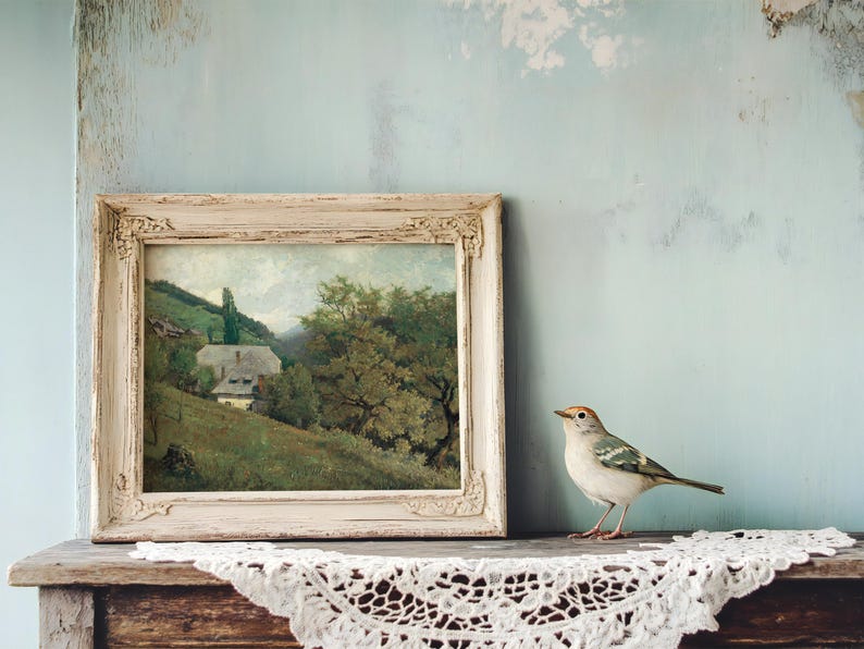 A small bird perches on a wooden shelf next to a rustic framed landscape painting. The setting feels vintage and serene with a lace cloth draped over the shelf.
