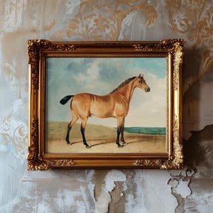 A framed painting of a horse with a sandy backdrop hangs on a textured, aged wall. The ornate gold frame contrasts with the worn wallpaper.