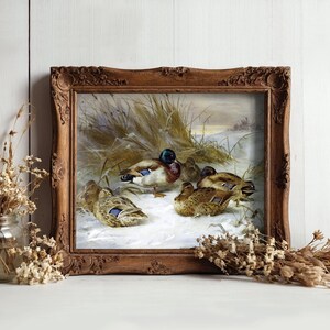A framed painting of ducks in a snowy field is set against a rustic wooden background. It is flanked by jars of dried flowers, creating a cozy, vintage feel.