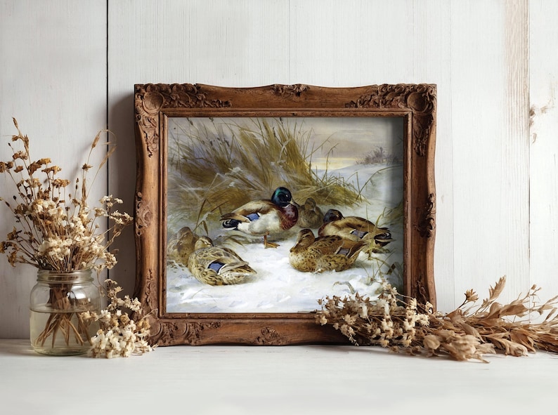 A framed painting of ducks in a snowy field is set against a rustic wooden background. It is flanked by jars of dried flowers, creating a cozy, vintage feel.