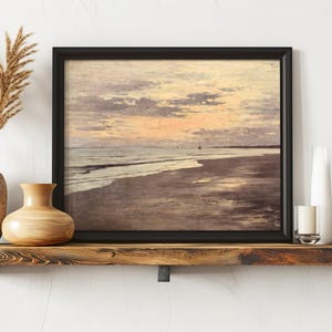 A framed painting of a serene beach at sunset, with gentle waves and pastel skies, displayed on a wooden shelf with vases and candles, evoking tranquility.