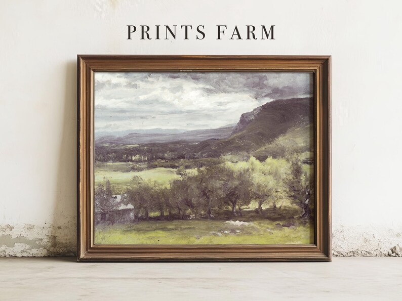 Framed landscape painting with cloudy sky and mountains, set against a plain wall. The scene conveys a calm, pastoral feel. Text above reads "Prints Farm."
