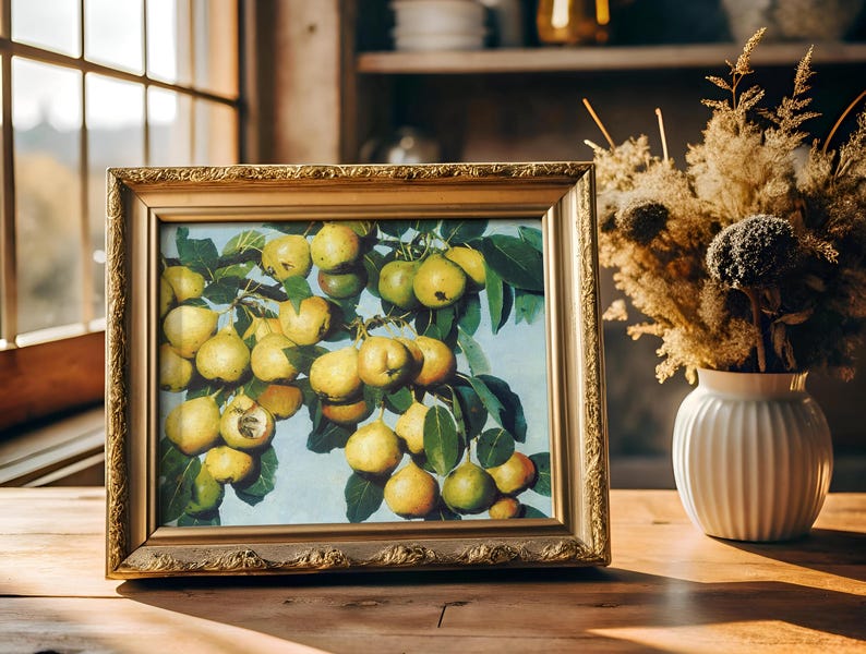 A framed painting of ripe pears on a branch, sits on a wooden table beside a vase of dried flowers. Sunlight streams through a window, creating a warm, cozy ambiance.