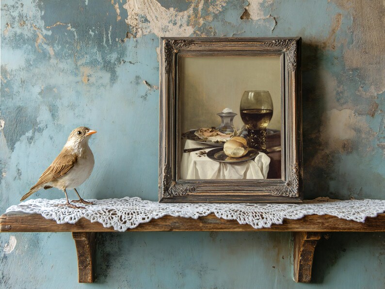A small bird perches on a lace-covered shelf beside a framed still life painting of a meal with wine, set against a textured blue wall.