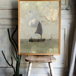 A framed painting of a sailboat on a calm sea with a cloudy sky. The painting is in a light wood frame and is hanging on a white wall.