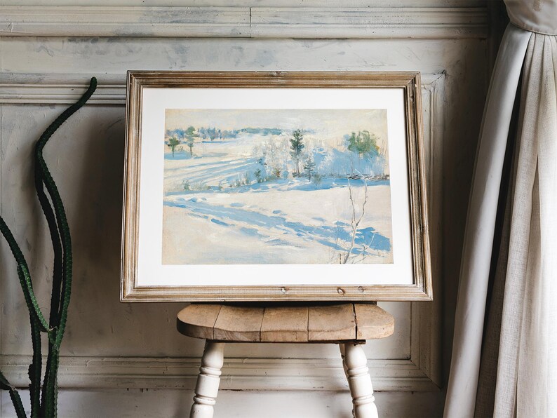 Framed landscape painting of a snowy field and distant trees on a wooden stool. Soft, natural light filters through beige curtains, evoking calm tranquility.