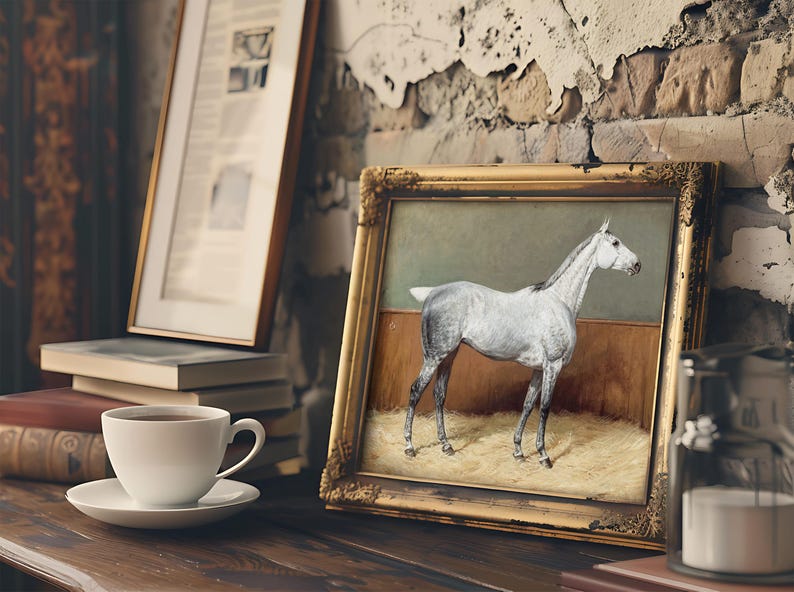 A framed painting of a white horse leans against a rustic, textured wall on a wooden shelf. Nearby, a cup of coffee and stacked books create a cozy atmosphere.