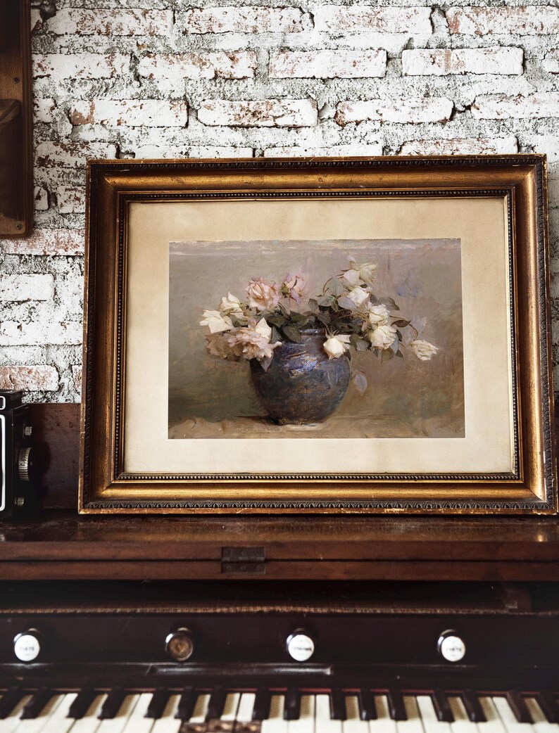 A framed painting of a bouquet of white roses in a blue vase. The roses are arranged in a loose, natural style, and the vase is simple and elegant. The painting is set against a soft, muted background.