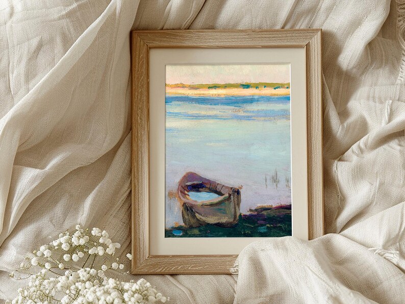 Framed painting of a boat on calm water, surrounded by soft beige fabric and delicate white flowers, evoking a serene and peaceful mood.