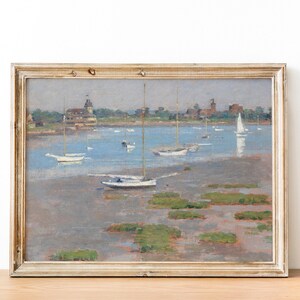 A framed painting depicting a seascape with sailboats anchored in a calm bay. The scene is painted in muted tones of blue, gray, and white, with a hint of green for the foliage on the shore. The painting captures a peaceful and serene moment on the water.