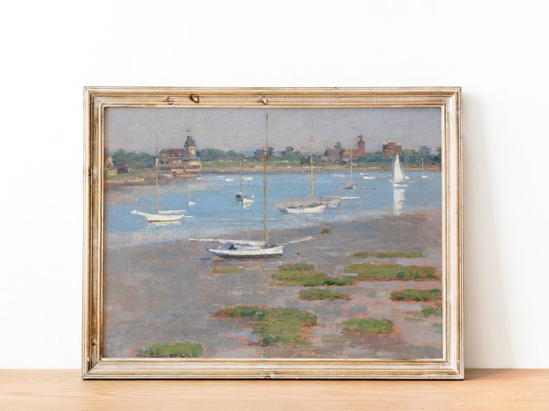 A framed painting depicting a seascape with sailboats anchored in a calm bay. The scene is painted in muted tones of blue, gray, and white, with a hint of green for the foliage on the shore. The painting captures a peaceful and serene moment on the water.