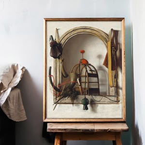 A framed painting on an easel shows a surreal still life with a birdcage, arched window, and hanging objects. The scene is set in a softly lit room.