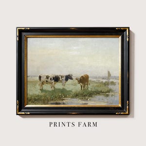 Framed painting of two cows grazing in a green meadow with a sailboat on a distant river under a cloudy sky. Text below reads "Prints Farm."