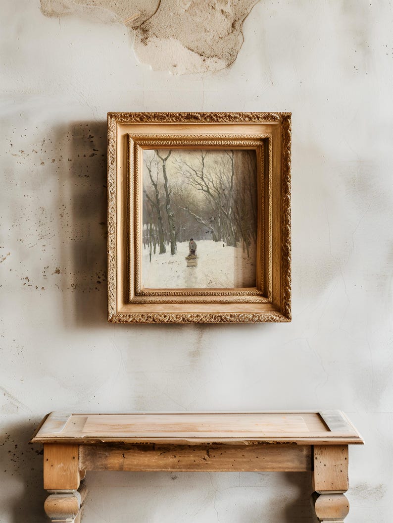 A vintage painting in an ornate gold frame hangs on a textured, weathered wall above a rustic wooden table. The painting depicts a snowy landscape with trees.
