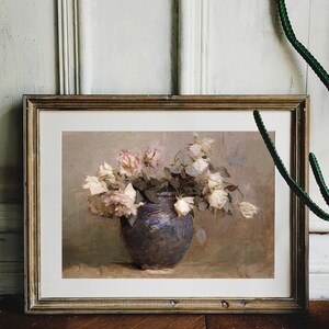 A painting of a bouquet of white and pink roses in a dark blue ceramic vase. The roses are arranged in a loose, natural style, and the vase is set on a table with a light brown surface.