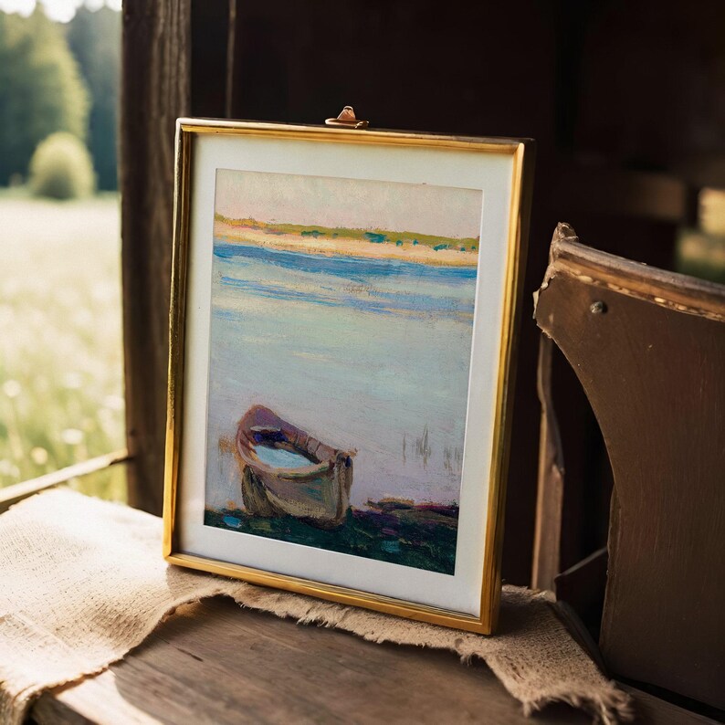 Framed painting of a boat on a calm lake under a golden sky, sitting on a rustic wooden bench with a burlap cloth, evoking tranquility.